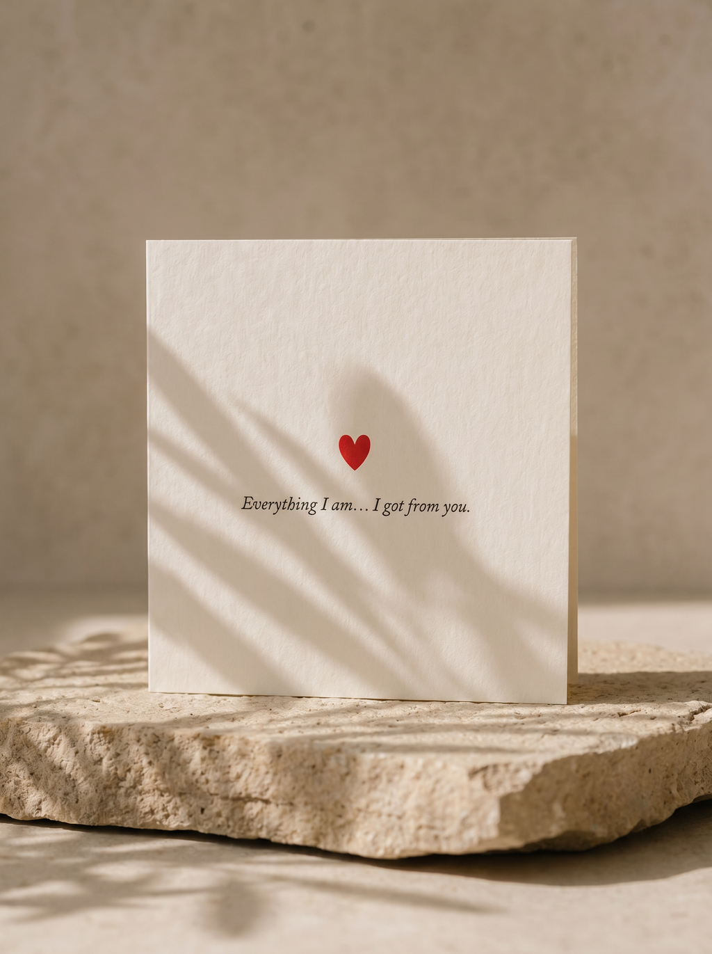 Card with a red heart and text on a stone surface with a beige background