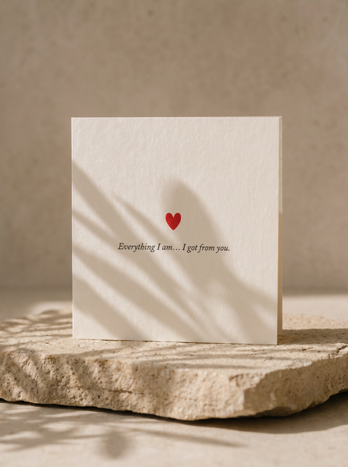 Card with a red heart and text on a stone surface with a beige background